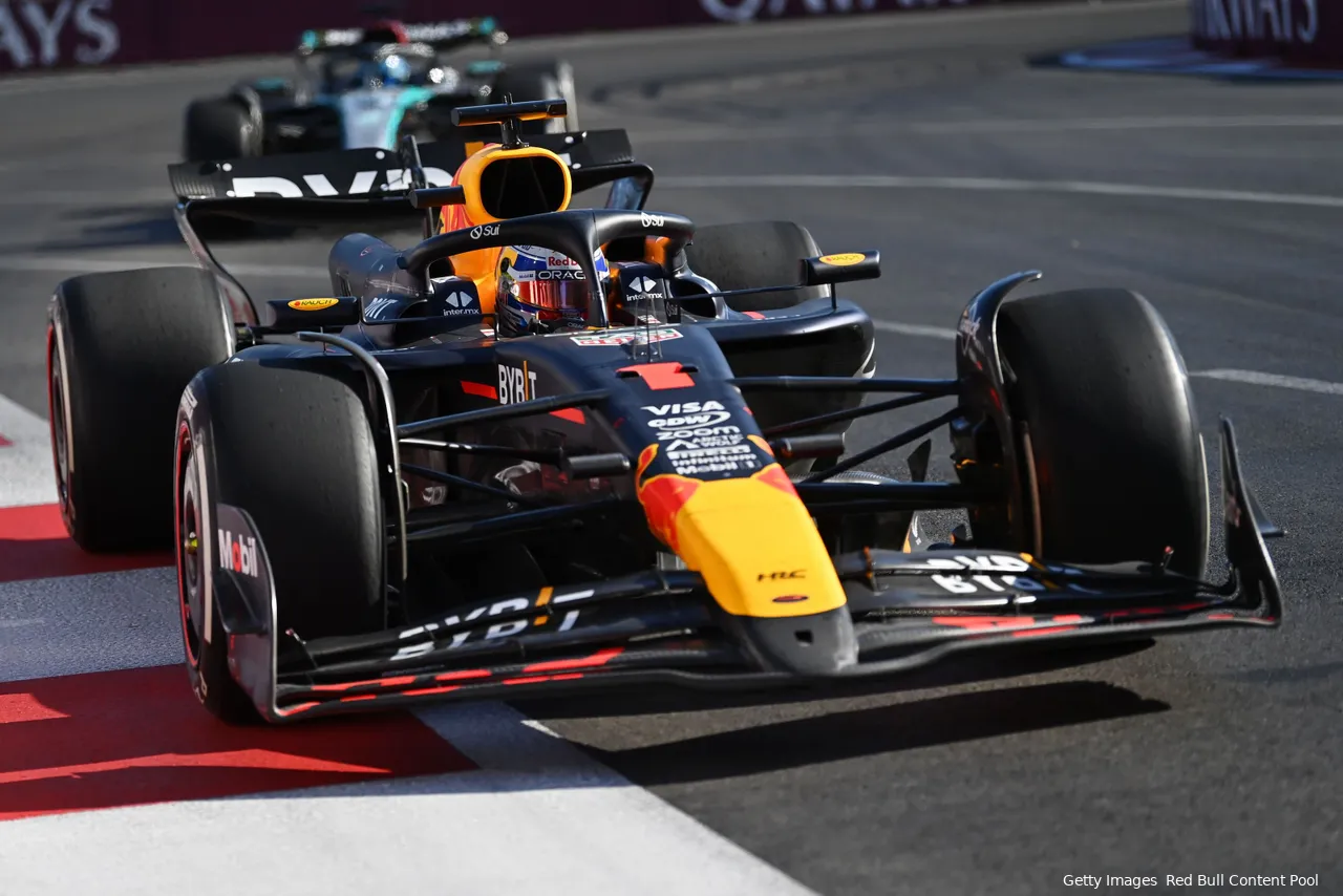 Max Verstappen exiting a corner, closely followed by George Russell's Mercedes in the background during the 2024 Azerbaijan Grand Prix.