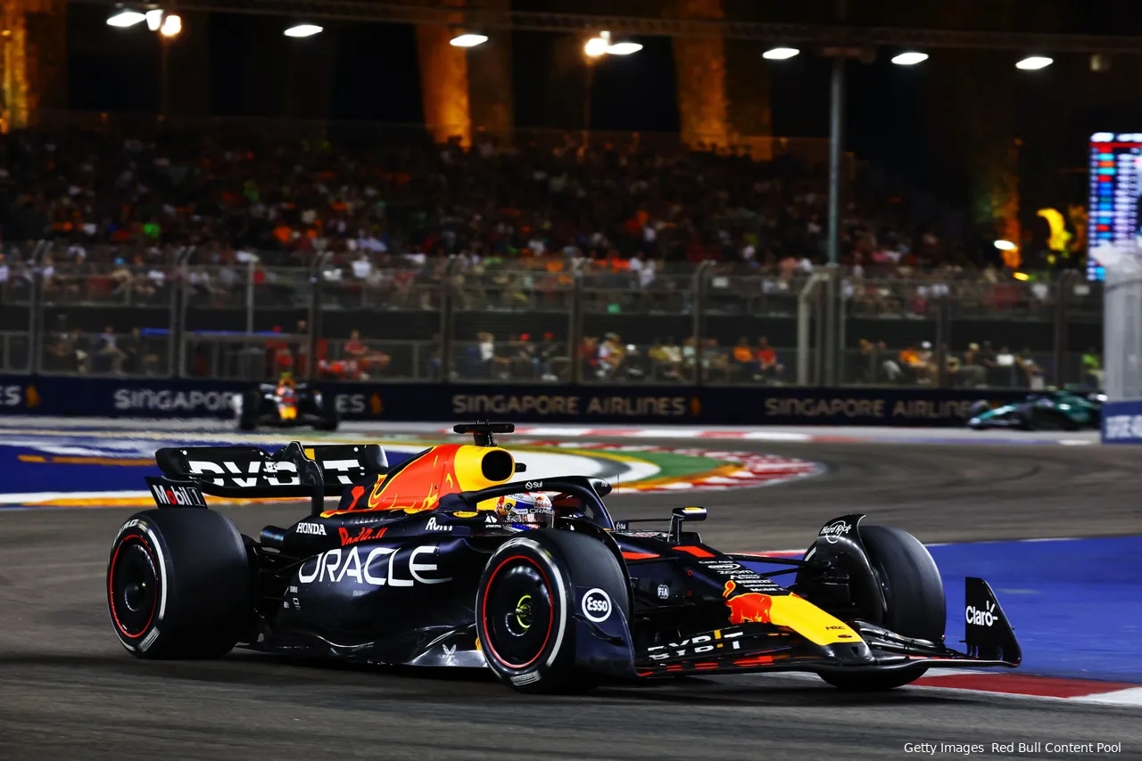 Max Verstappen in his RB19 at turn 3 during the 2023 Singapore GP, with turns 1 and 2, barriers, and grandstands in the background.