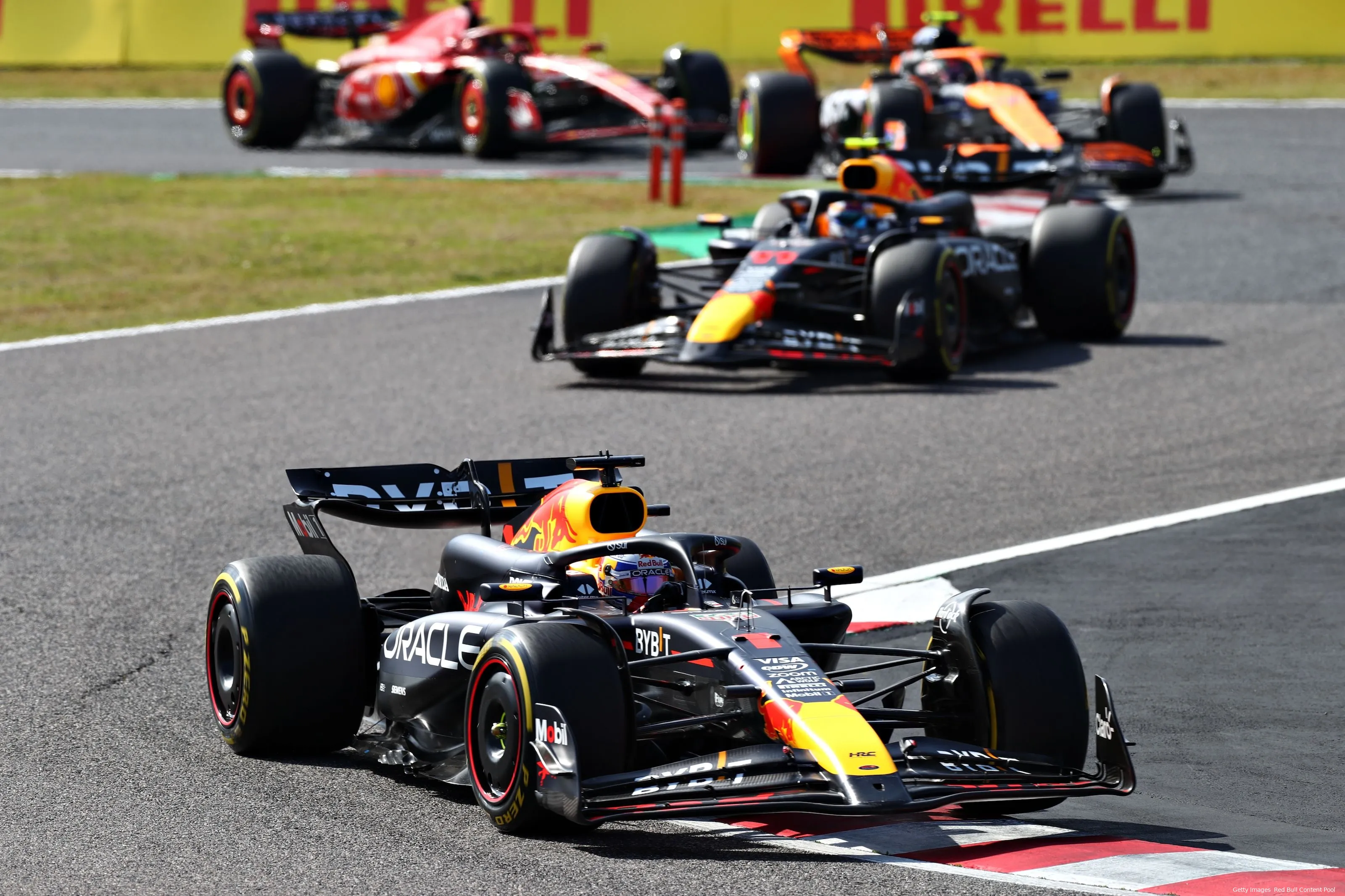 Max Verstappen, followed by Sergio Perez, followed by Lando Norris, followed by Carlos Sainz around the last two turns at Suzuka Circuit