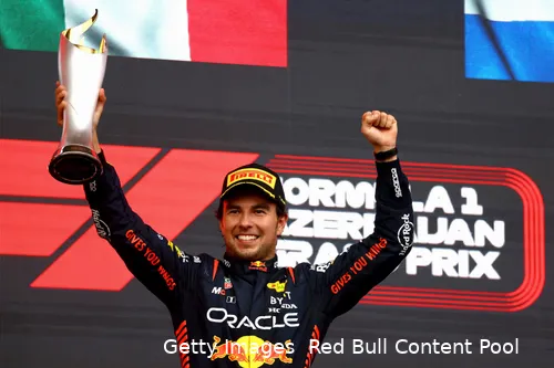 Sergio Perez celebrates on the top step of the podium, raising the trophy after winning the 2023 Azerbaijan Grand Prix in Baku.