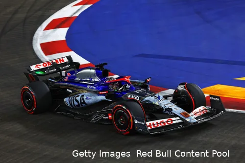 Daniel Ricciardo in his special livery F1 car with soft tires riding the curb on a flying lap at the 2024 Singapore Grand Prix.