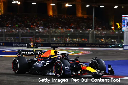 Max Verstappen in his RB19 at turn 3 during the 2023 Singapore GP, with turns 1 and 2, barriers, and grandstands in the background.