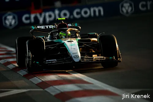 Lewis Hamilton driving his Mercedes over the white and red curb at the Baku City Circuit during golden hour, with advertising banners visible in the background.