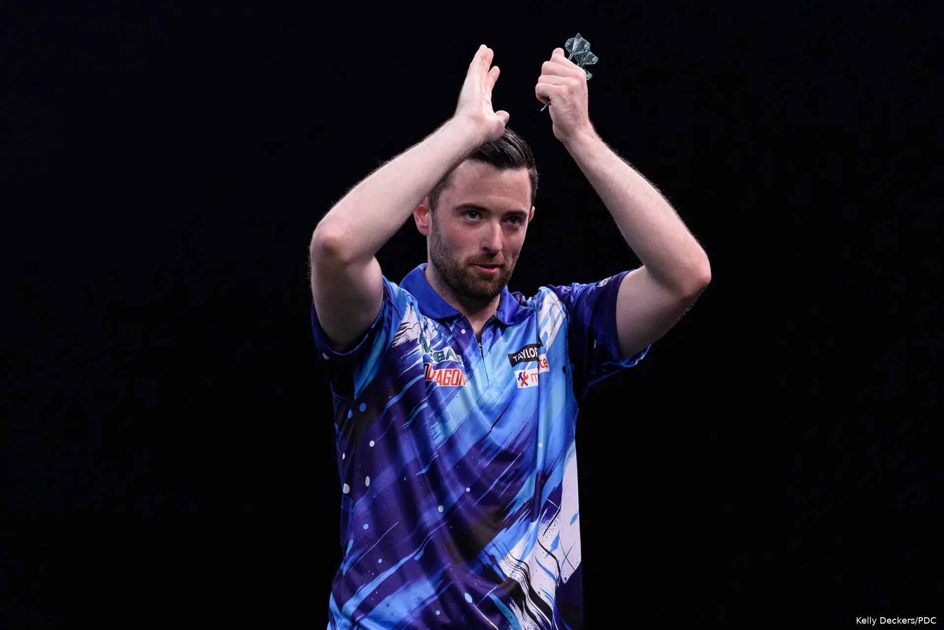 Luke Humphries applaudisseert naar het publiek.