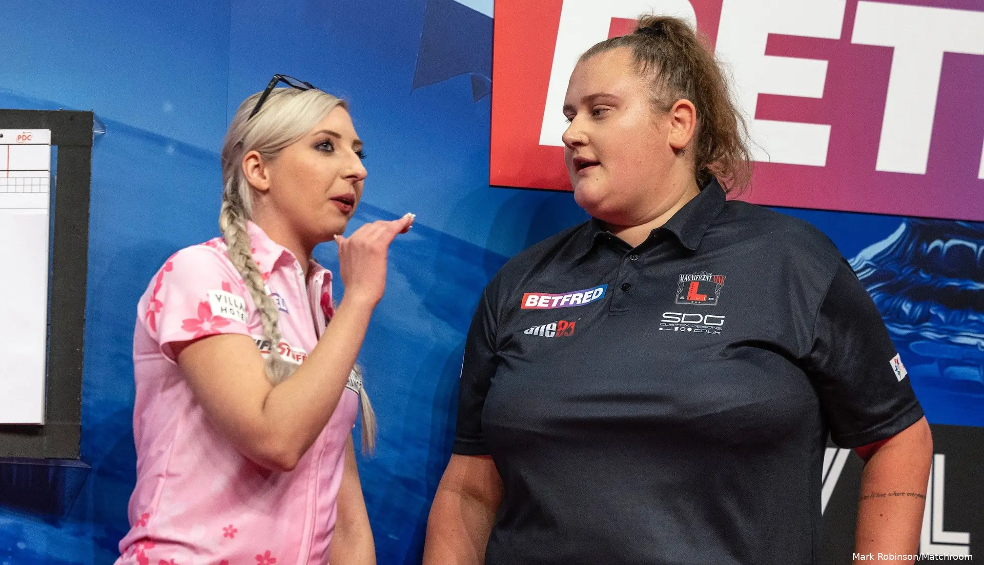 Fallon Sherrock en Beau Greaves praten met elkaar op het podium