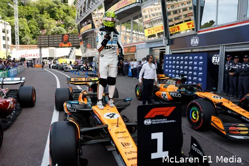 <i>Norris viert zijn poleposition in Monaco staand op zijn bolide.</i>