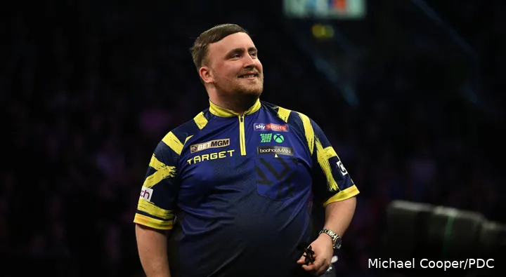 Luke Littler lacht richting het publiek.