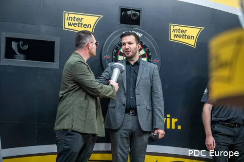 Brzezinski doet alsof hij zingt in een opblaasbare microfoon van darts Damon Heta op het podium.