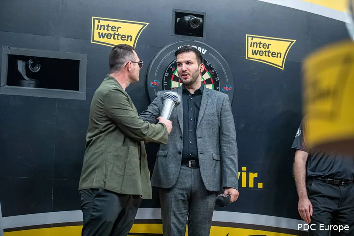 Brzezinski doet alsof hij zingt in een opblaasbare microfoon van darts Damon Heta op het podium.