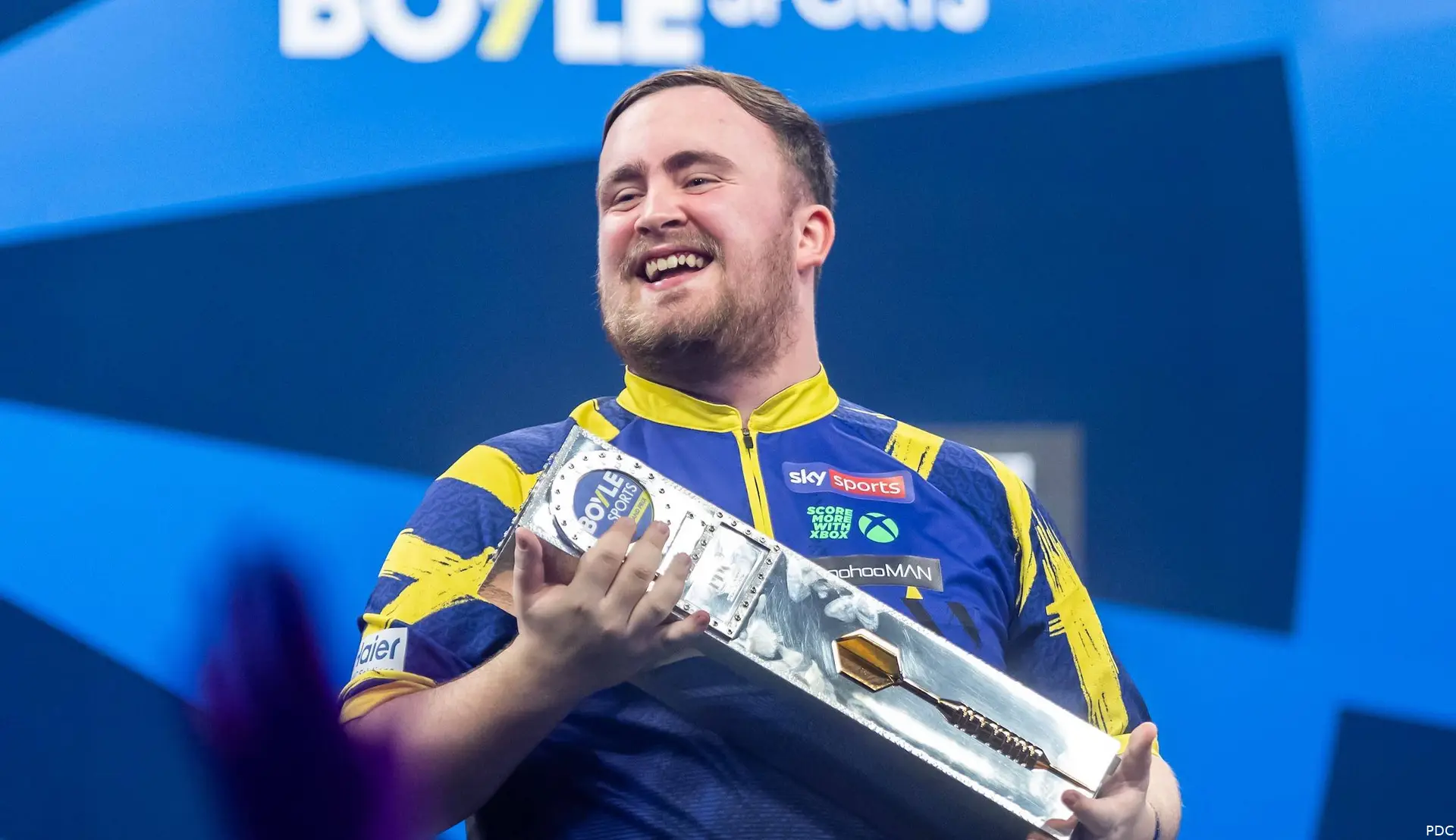 Luke Littler poses with the trophy.