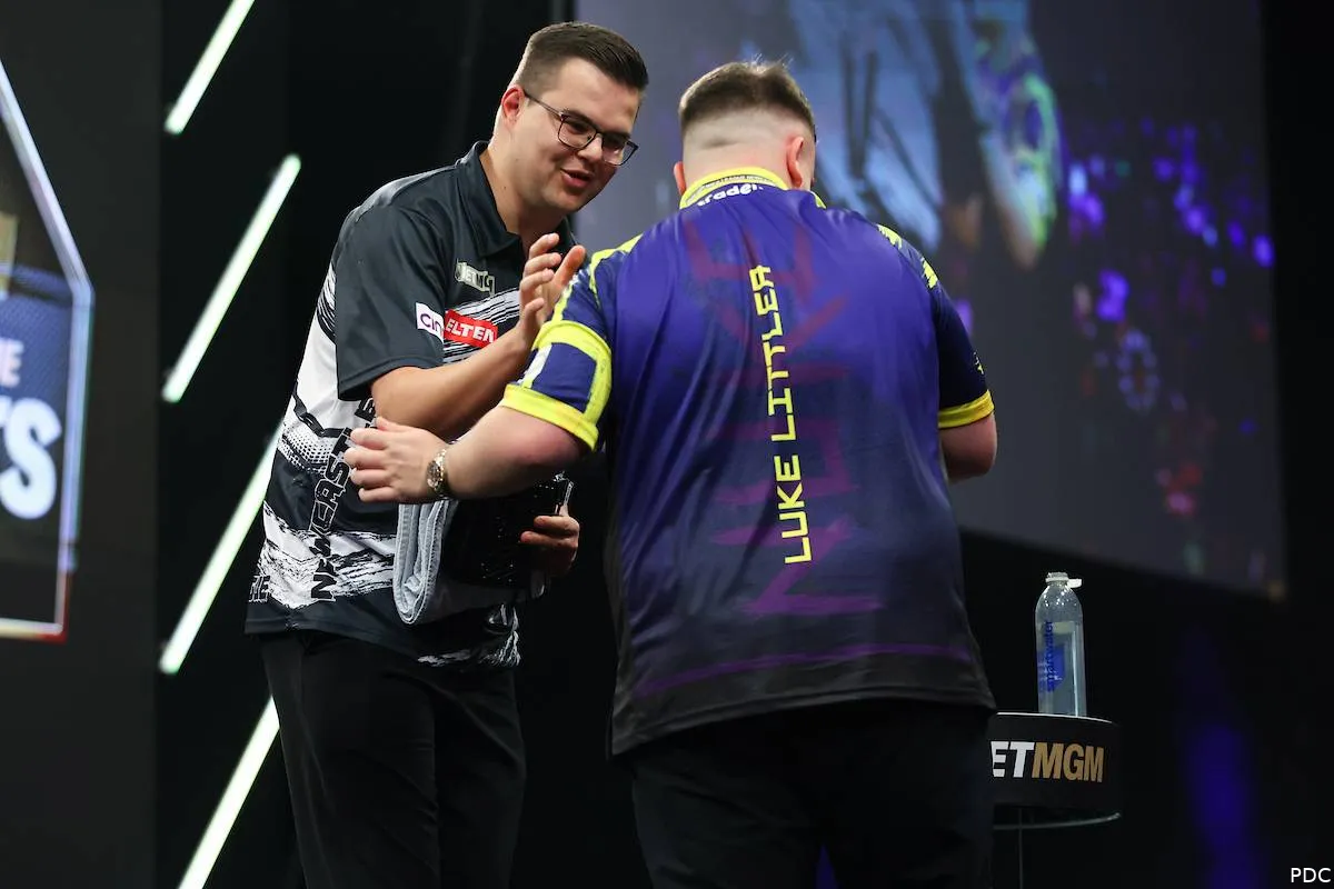 Van Veen en Littler schudden elkaar de hand na de wedstrijd op het podium.