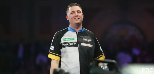 Chris Dobey lacht richting de camera.