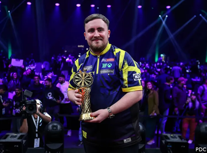 Luke Littler hält die Trophäe nach seinem Sieg bei den Saudi Arabia Darts Masters 2026 in den Händen.