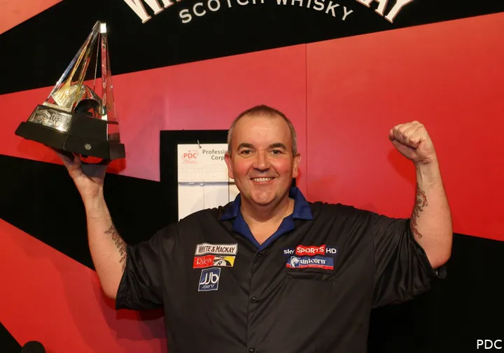 Phil Taylor reckt einen Titelpokal in die Höhe