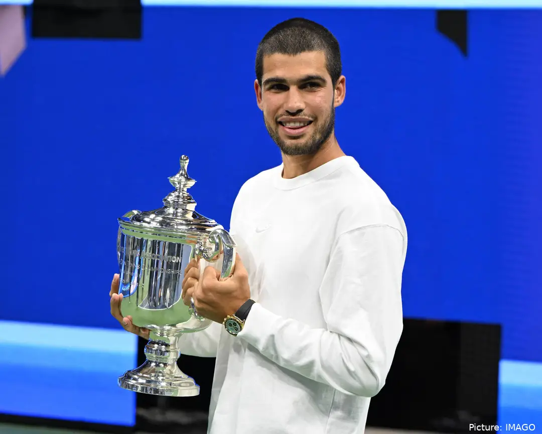 Carlos Alcaraz holding the US Open trophy while smiling