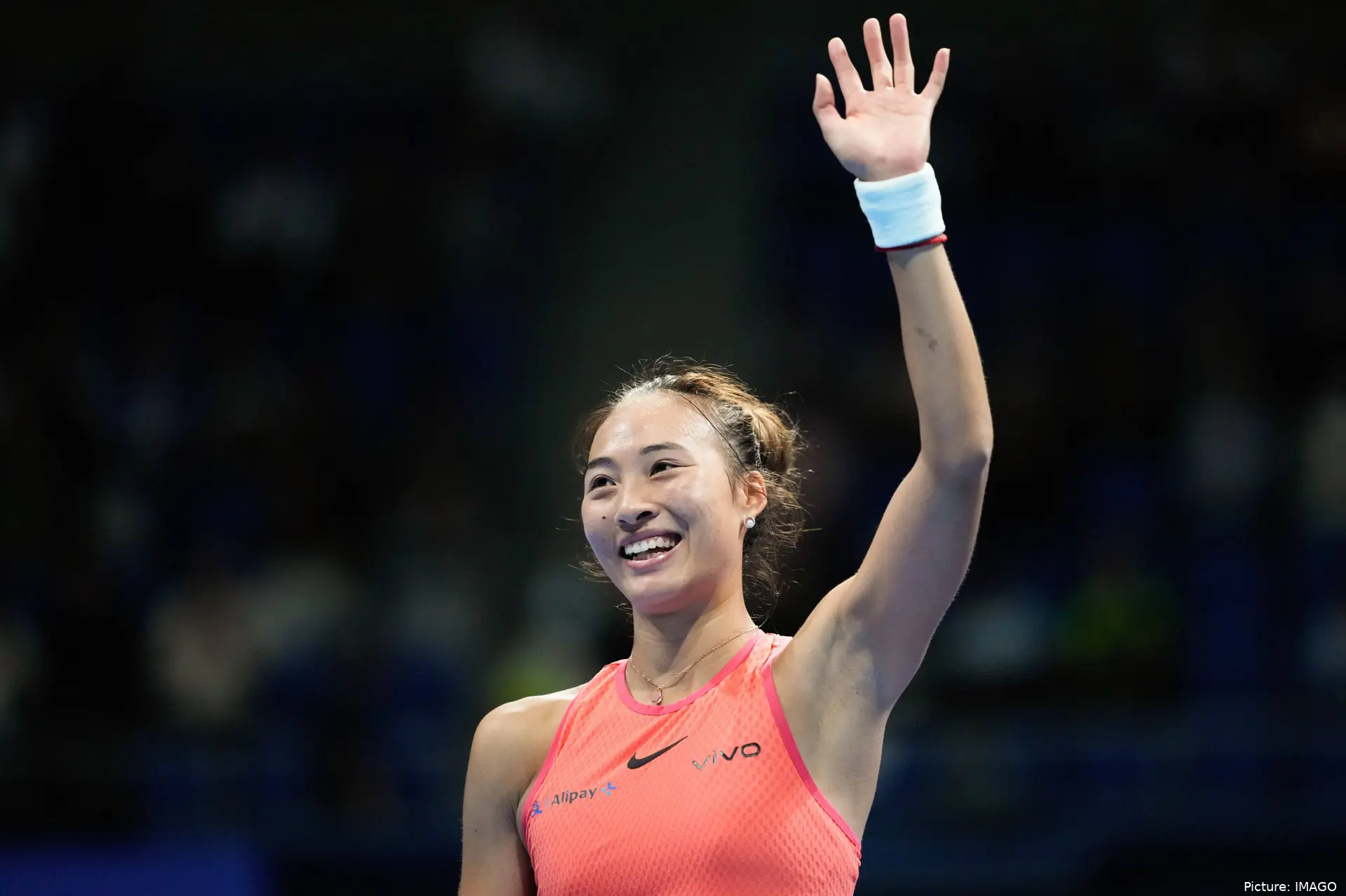 Zheng raises her left arm to greet the crowd at the WTA 1000 Wuhan Open