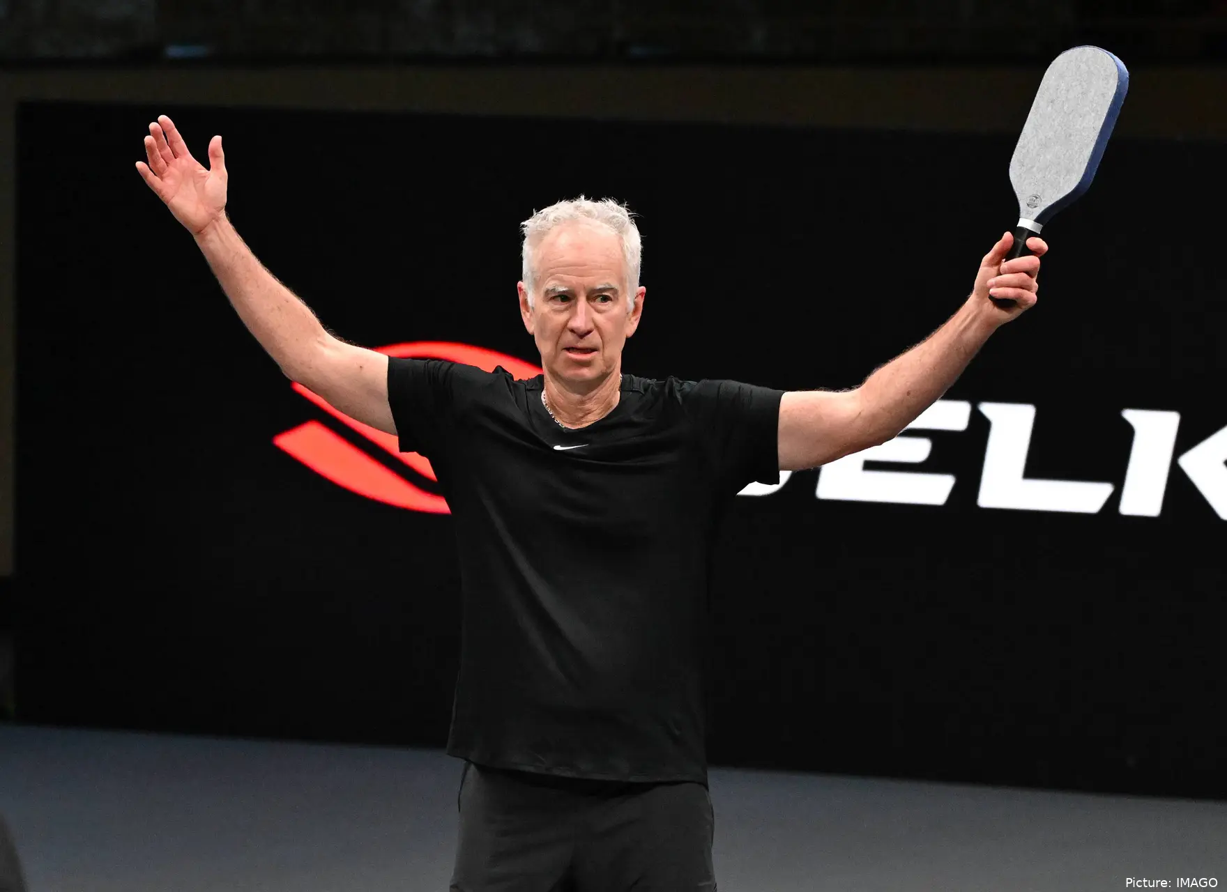 John McEnroe raises arm.