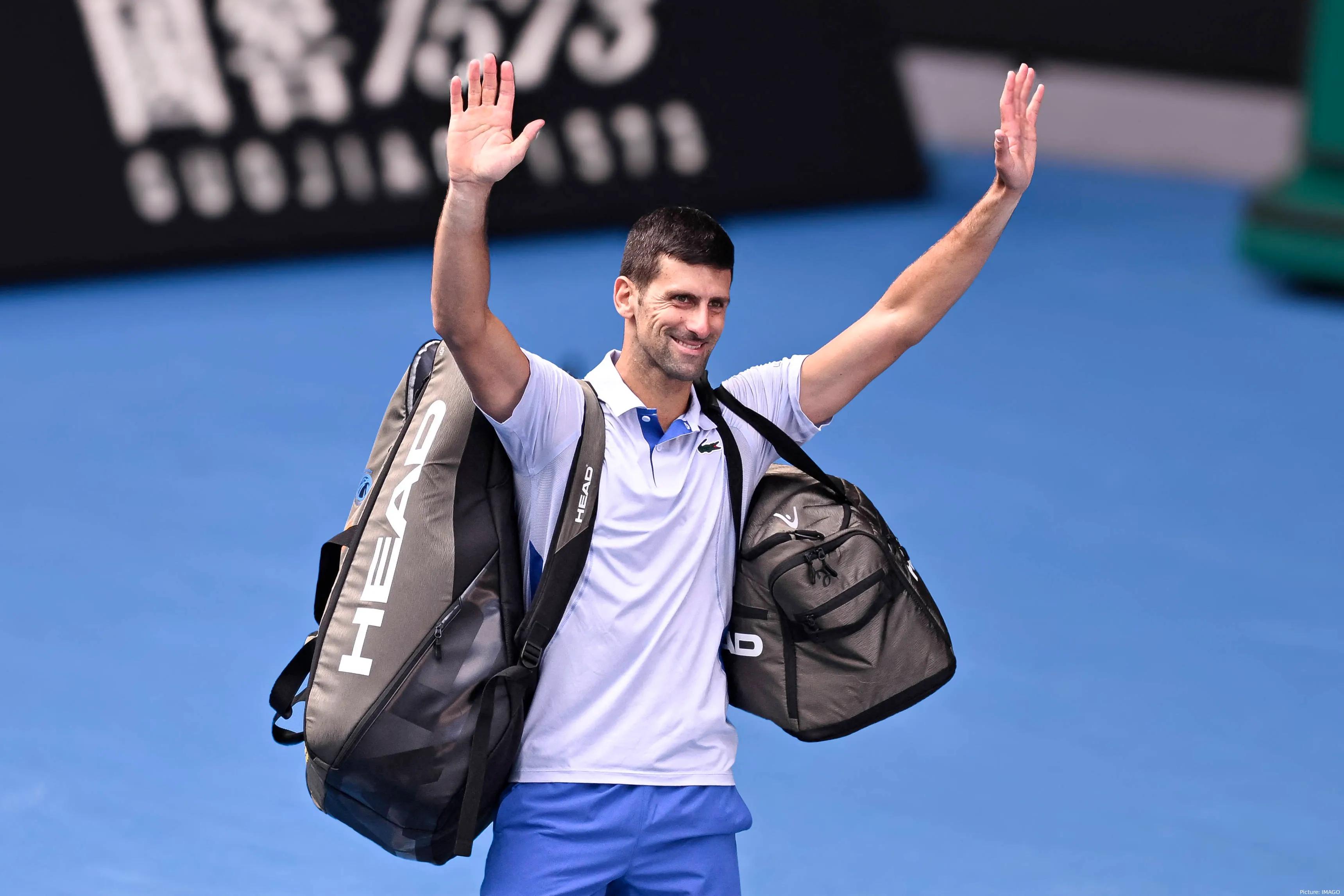 Bild Novak Djokovic, Arme erhoben, Taschen um Schultern grüßt Fans&lt;br&gt;