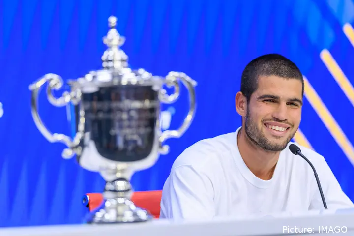 Alcaraz smiles next to his US Open trophy at the press conference.