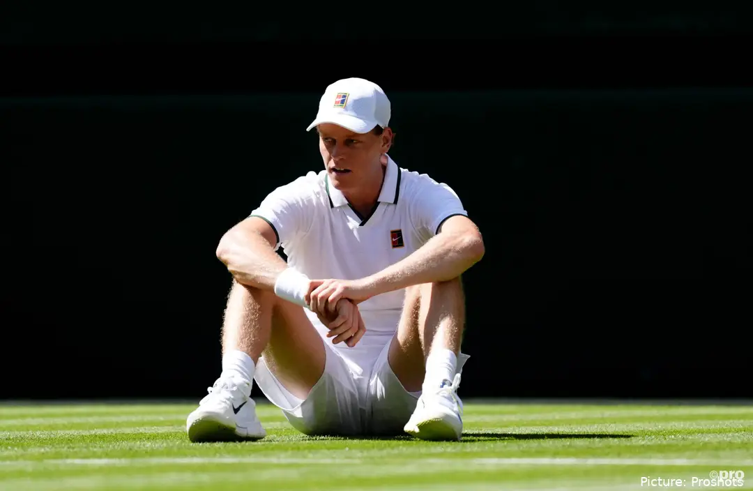 Jannik Sinner sits on the grass at Wimbledon.