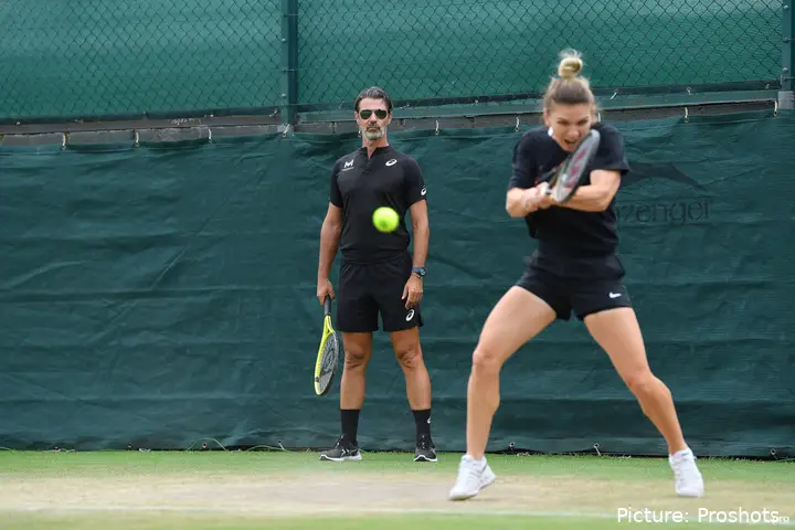 Patrick Mouratoglou, in the background, watches Simona Halep during a practice session.
