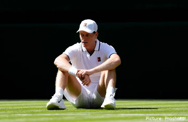 Jannik Sinner sits on the grass at Wimbledon.