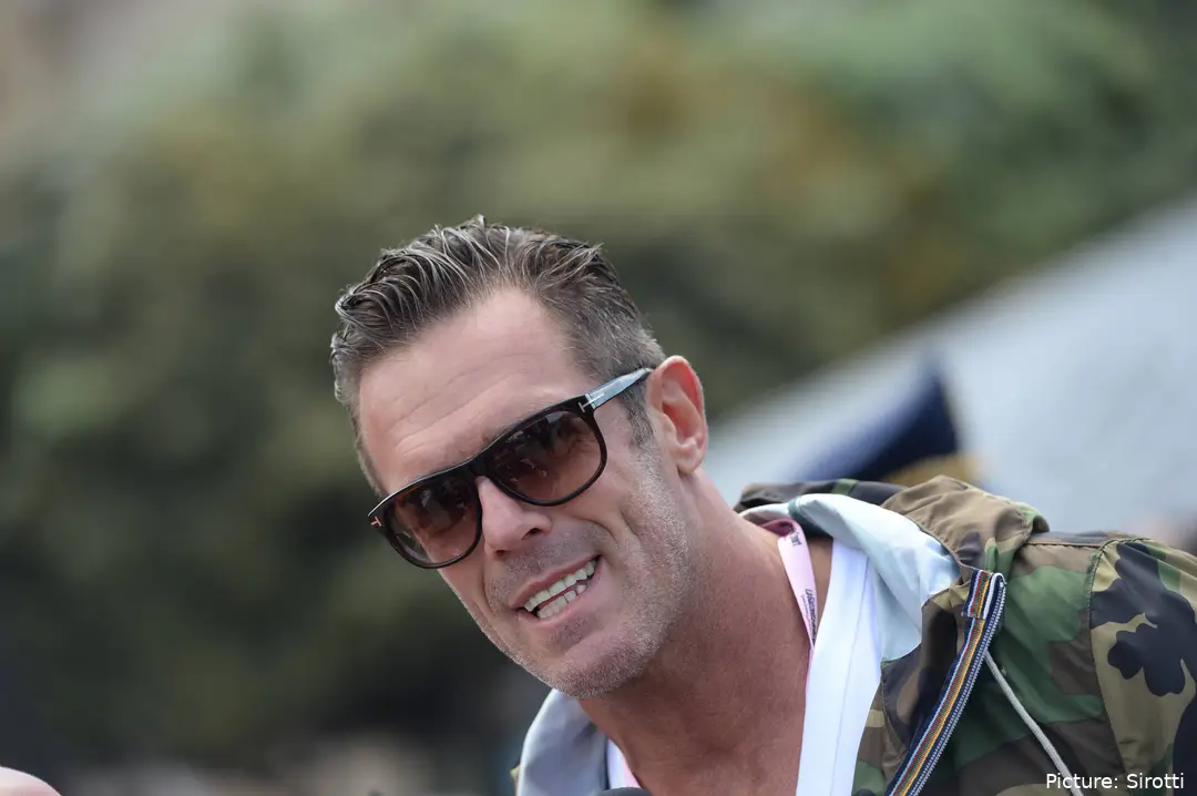 Mario Cipollini, vestido de calle con unas gafas de sol y sonriendo