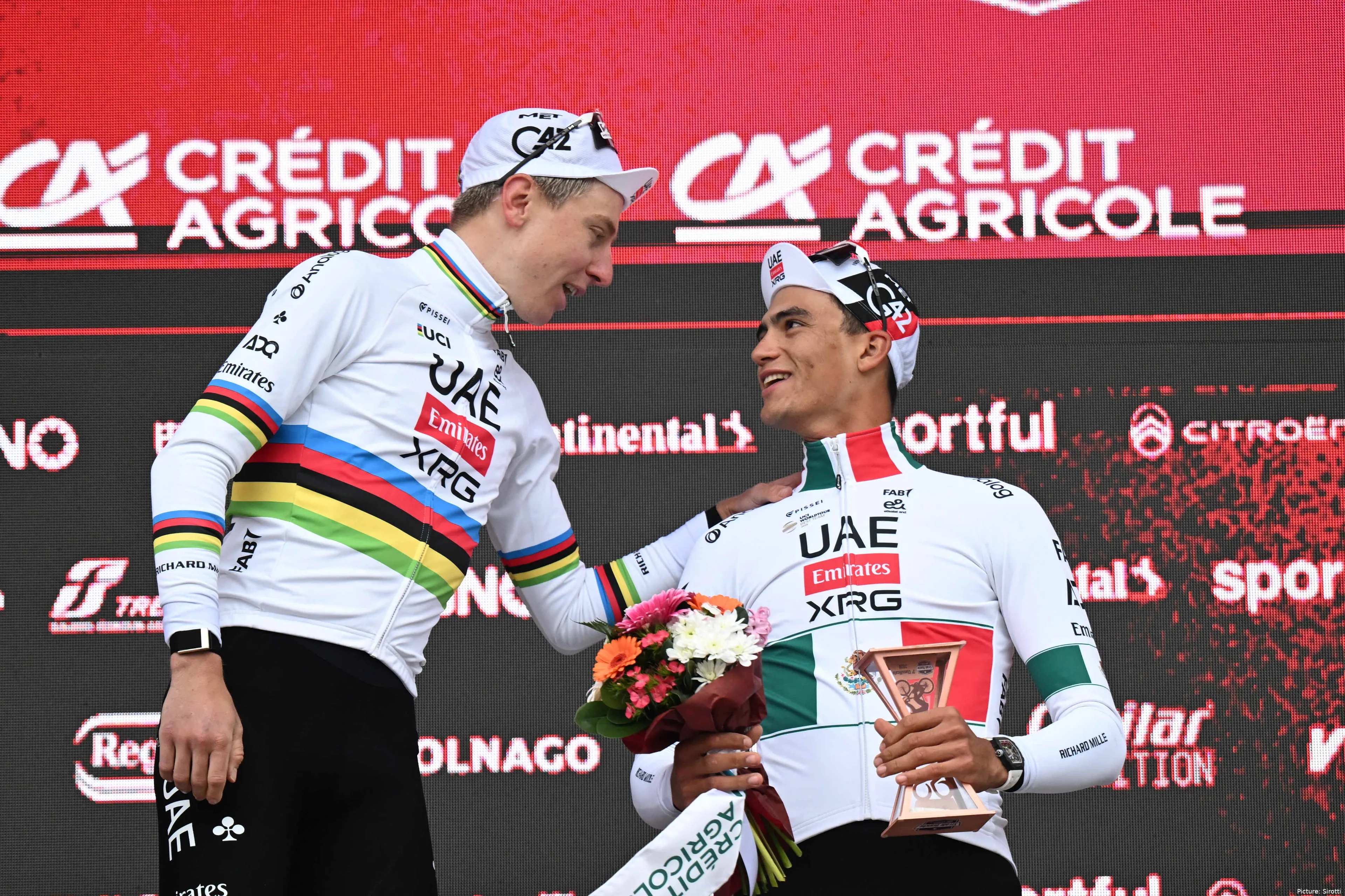 Tadej Pogacar and Isaac del Toro embrace on the podium after Strade Bianche 2026