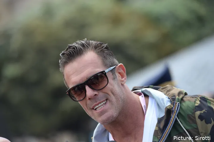 Mario Cipollini, vestido de calle con unas gafas de sol y sonriendo