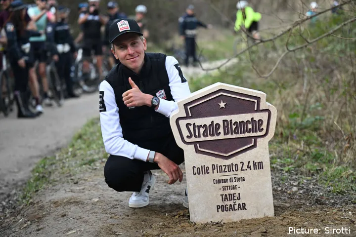 Tadej Pogacar posa junto ao seu marco à beira da estrada antes da Strade Bianche 2026