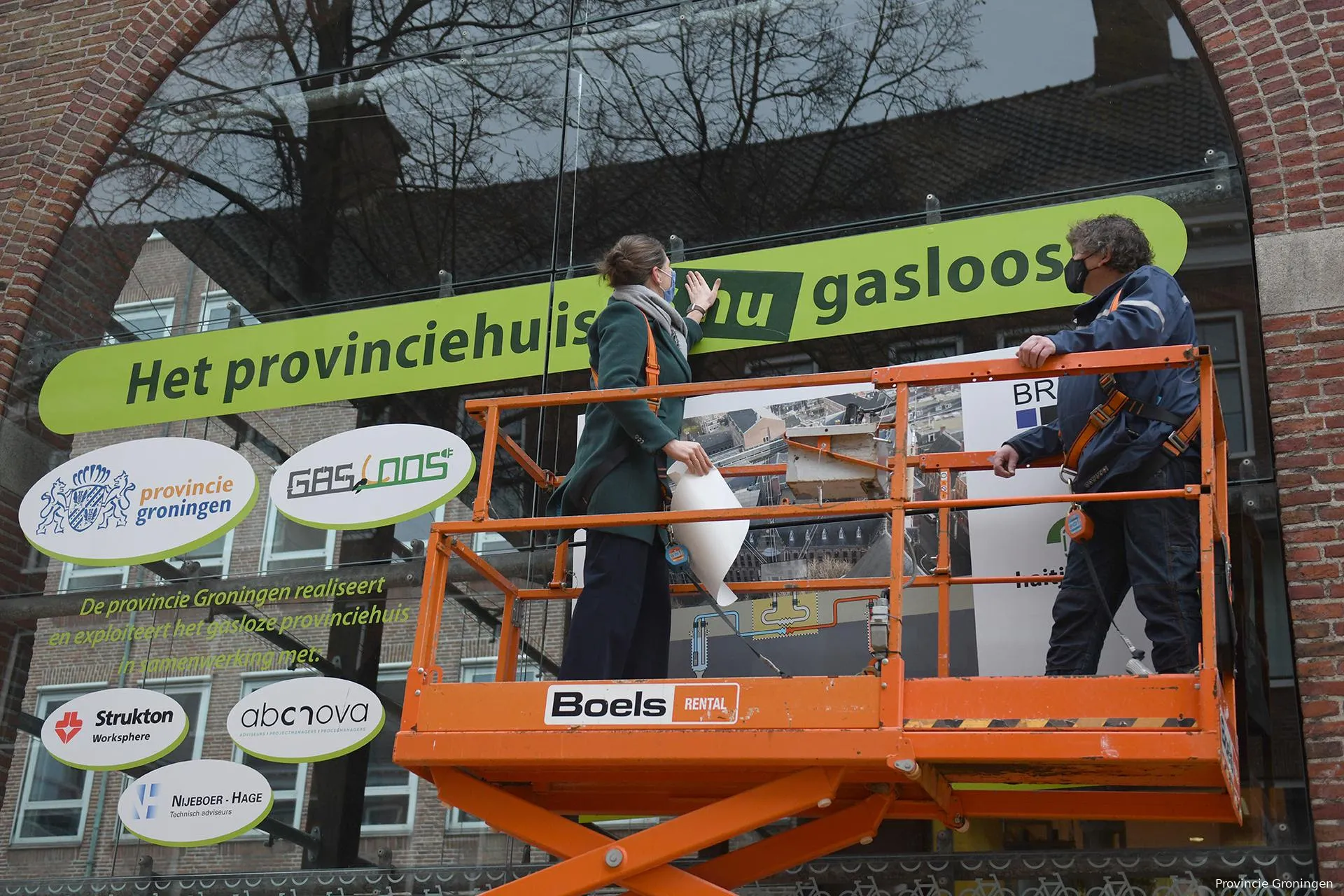 gedeputeerde fleur graper van koolwijk plakt de sticker het provinciehuis is nu gasloos op een bouwbord