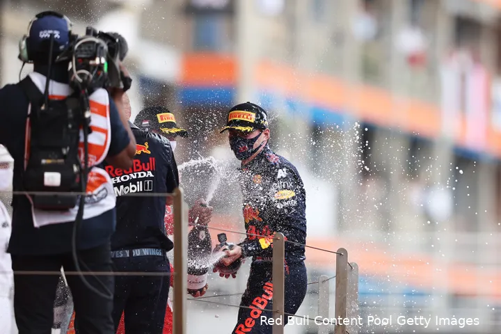 <i>Max Verstappen spuit champagne op het podium na in 2021 voor het eerste de Grand Prix van Monaco te winnen.</i>