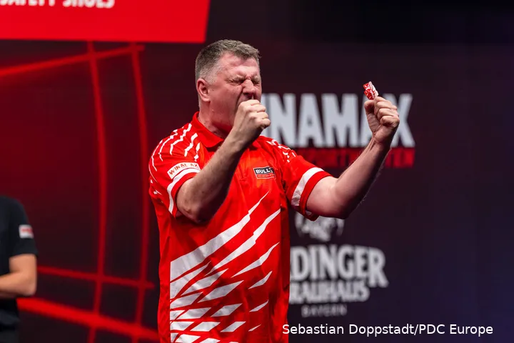 Krzysztof Ratajski celebrates broadly with his arms wide.