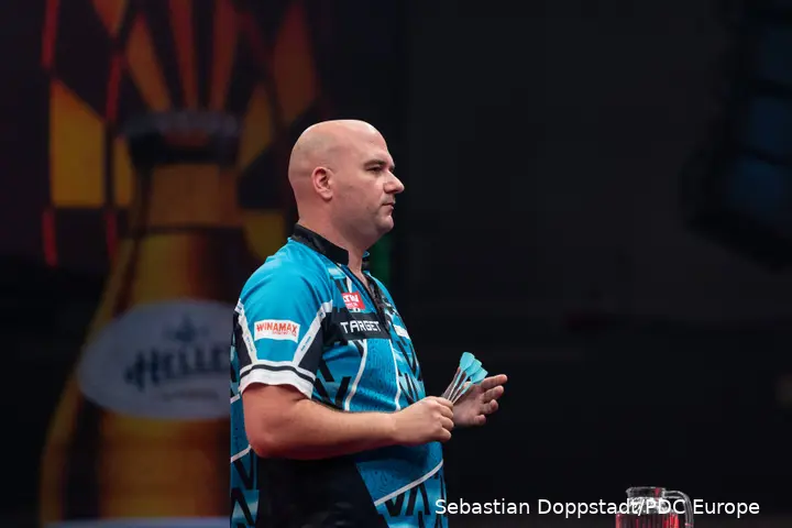 Rob Cross holds darts.