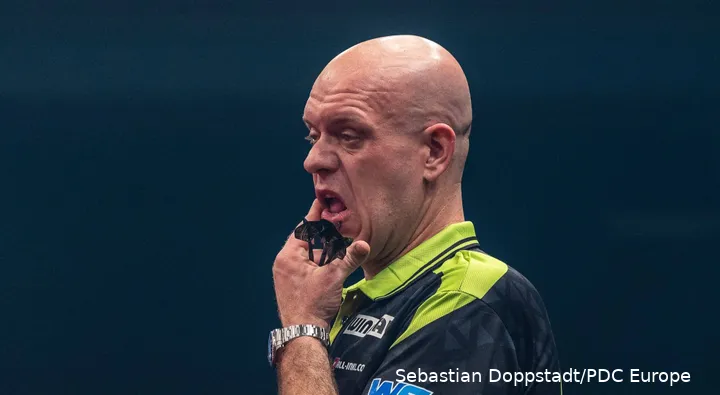 Michael van Gerwen kijkt beduusd terwijl hij zich over zijn wang wrijft.