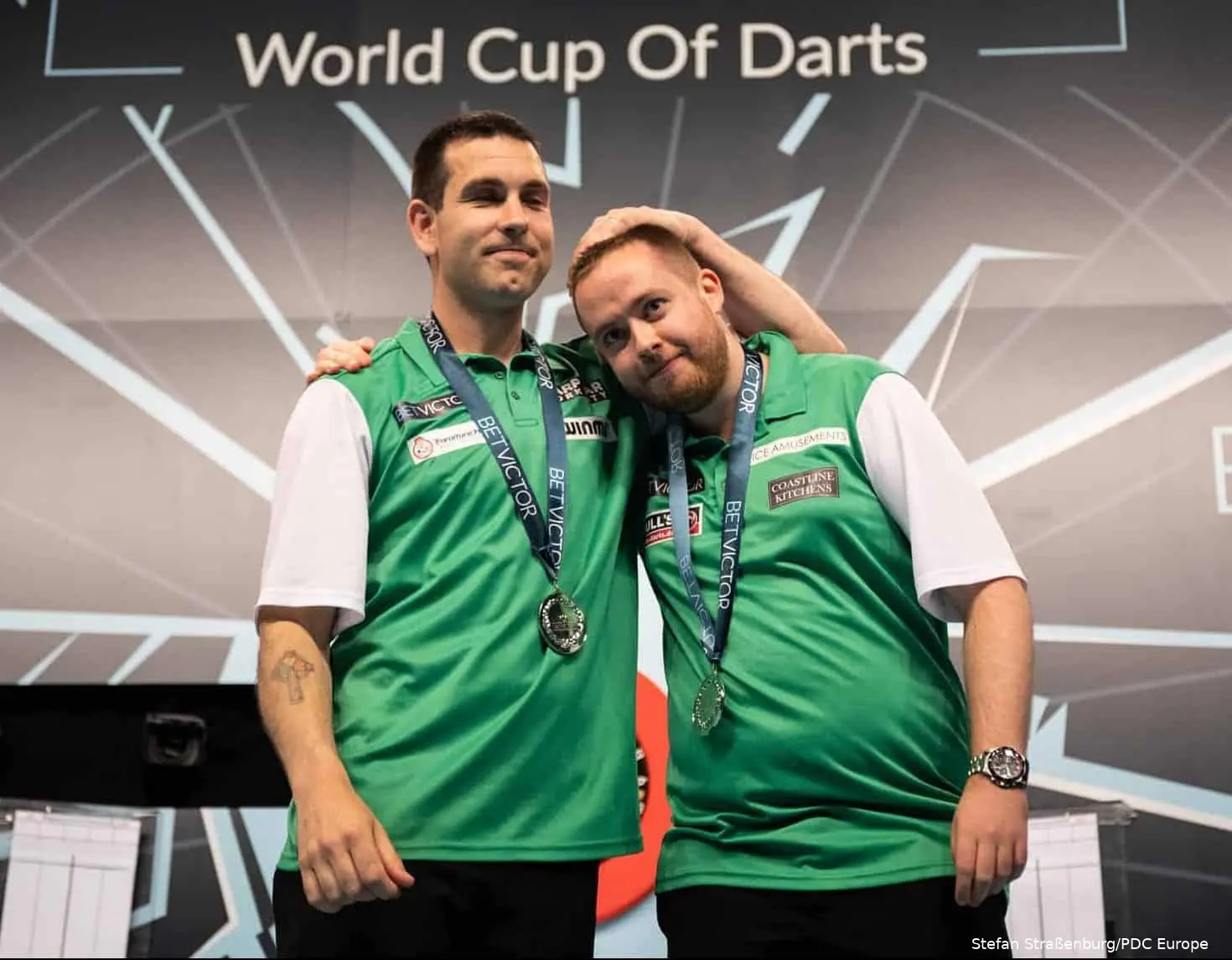 William O'Connor en Steve Lennon omhelzen elkaar op het podium na de verloren finale op de World Cup of Darts in 2019.