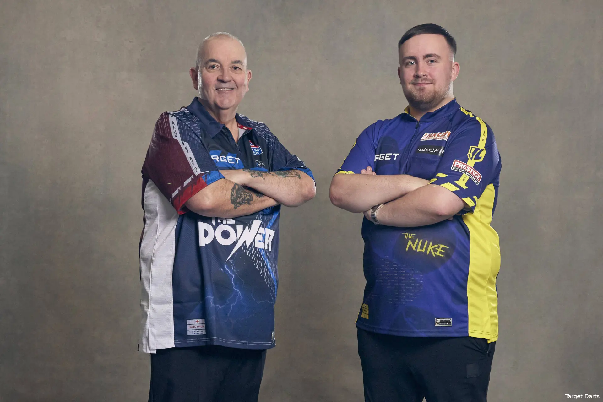 Luke Littler und Phil Taylor posieren nebeneinander mit verschränkten Armen.