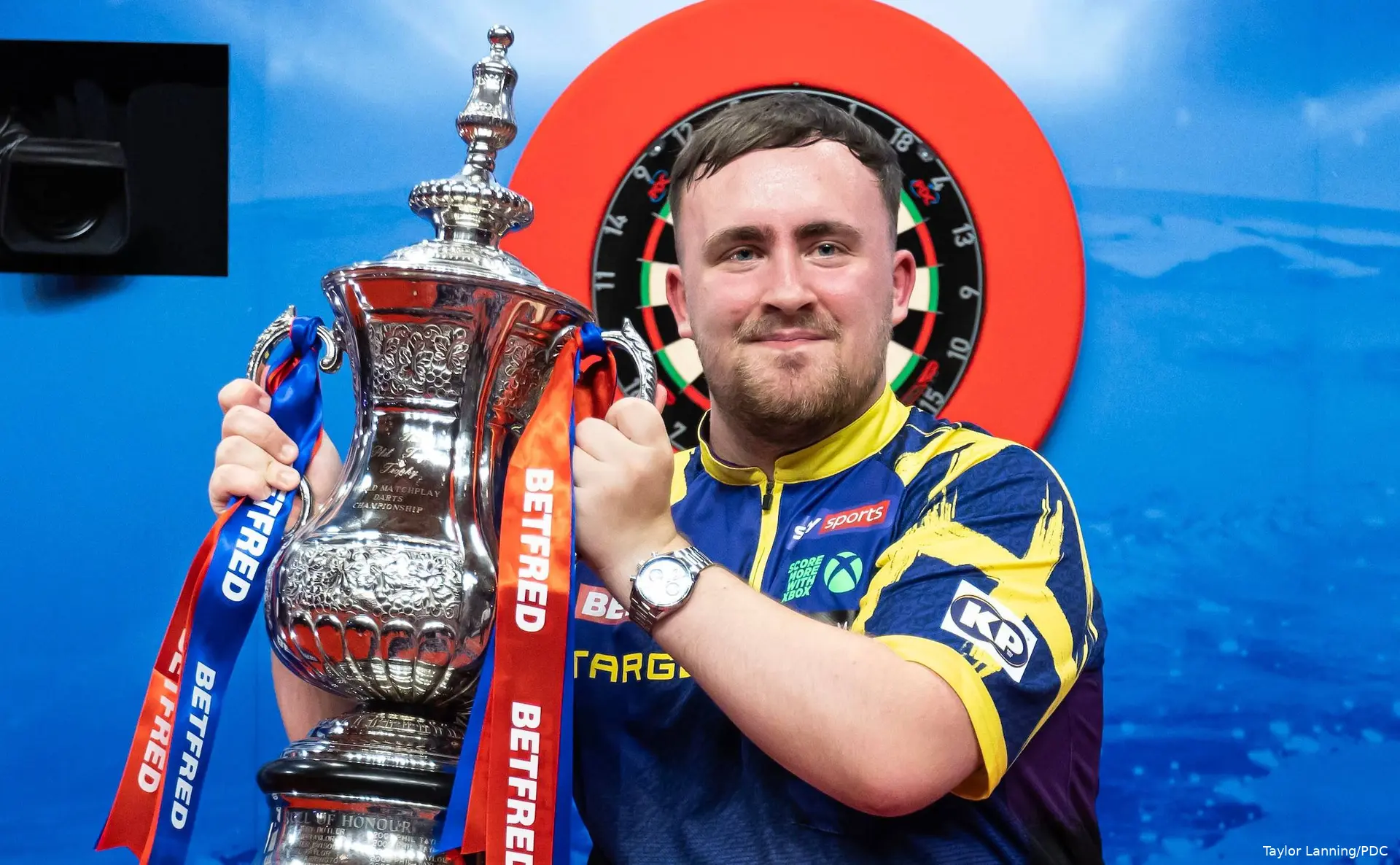 Luke Littler shows off the Phil Taylor Trophy as the World Matchplay 2026 champion