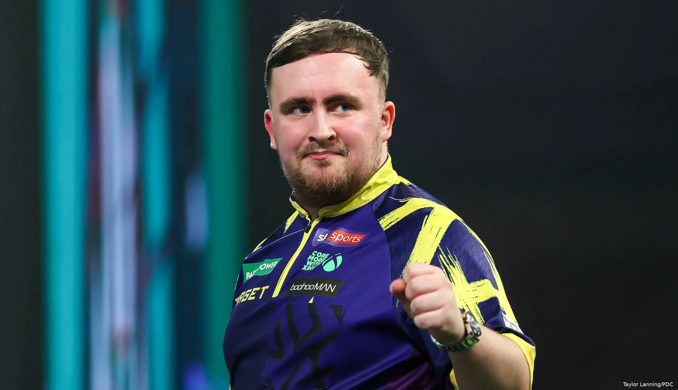 Luke Littler balt zijn vuist op het podium