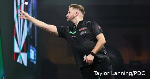Arno Merk throws his darts using his hand towards the board.