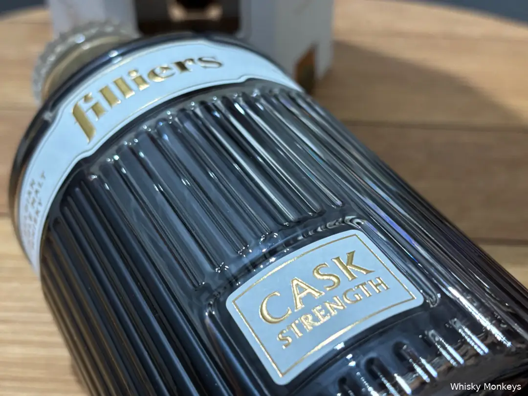 Een fles Filliers Cask Strength whisky met op een whiskyvatdeksel