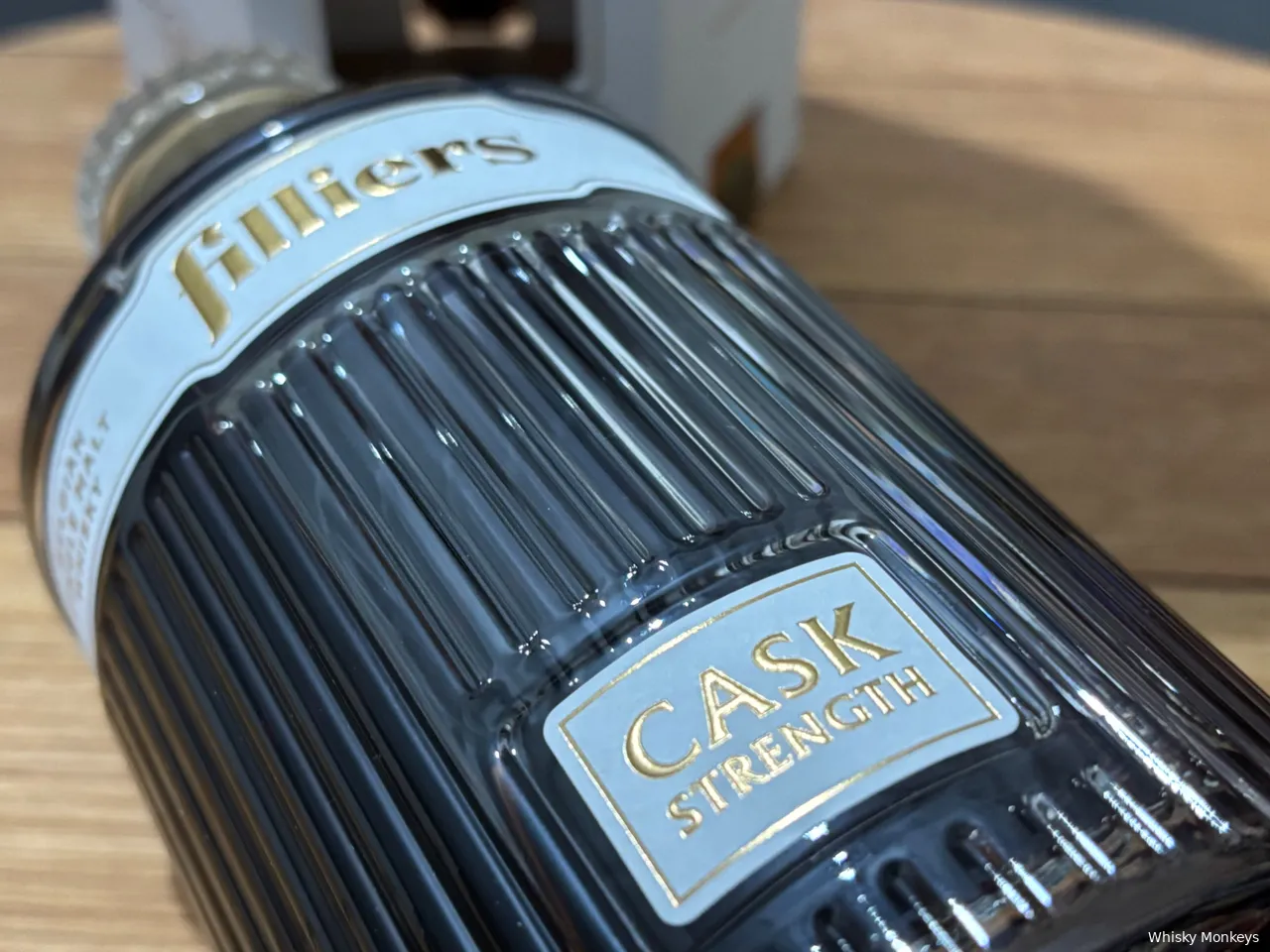 Een fles Filliers Cask Strength whisky met op een whiskyvatdeksel