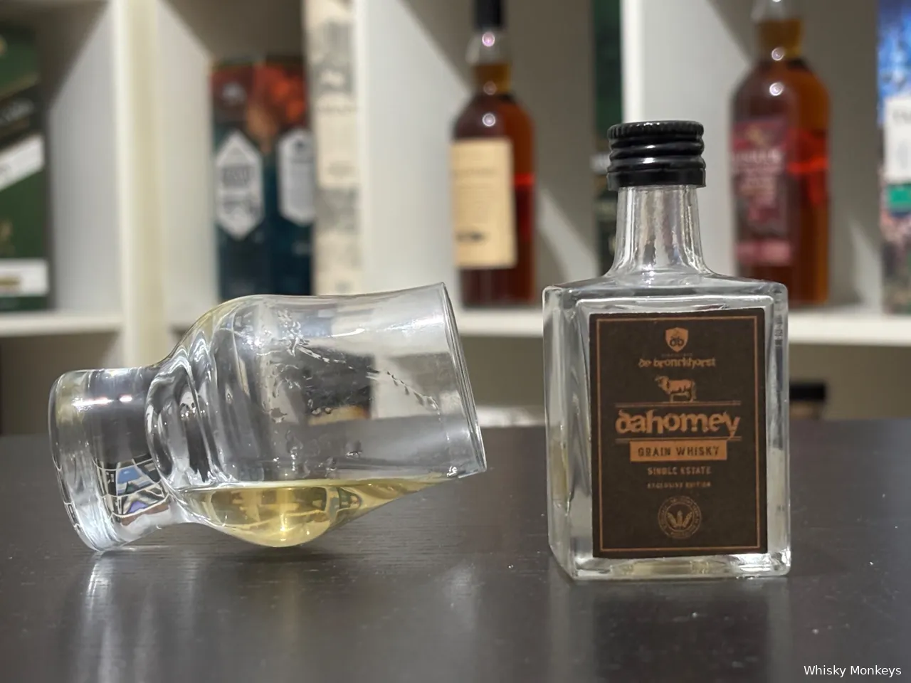 dahomey peated grain fles op een tafel met een glas whisky