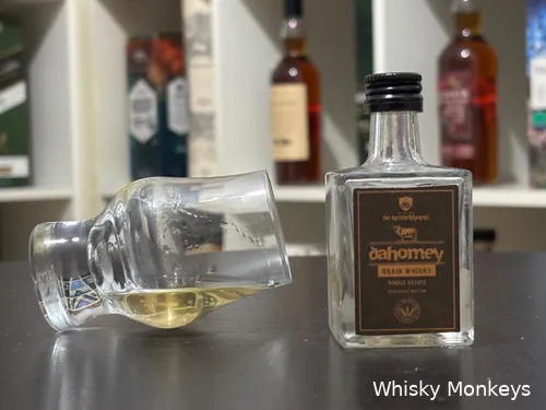 dahomey peated grain bottle on a table with a glass of whisky