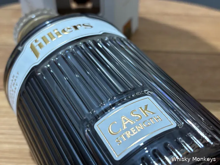 Een fles Filliers Cask Strength whisky met op een whiskyvatdeksel