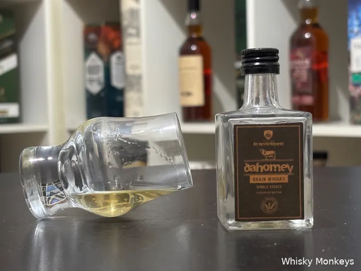 dahomey peated grain bottle on a table with a glass of whisky