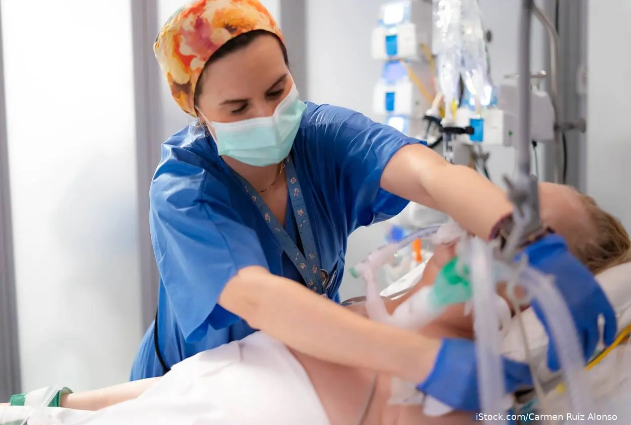 Nurse in mask with ventilated patient in hospital bed iStock-2207071541