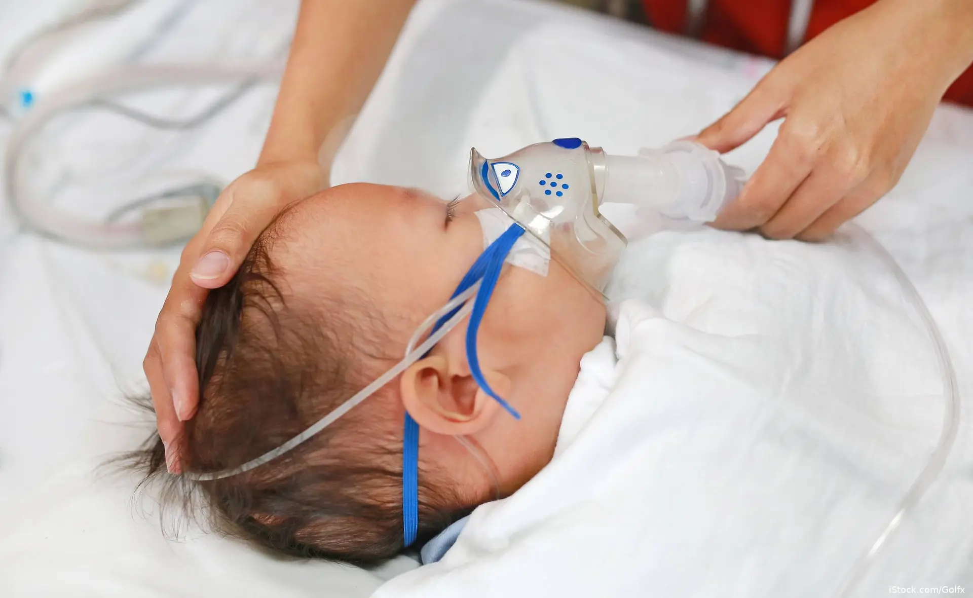 Infant with a face mask on and a caregiver