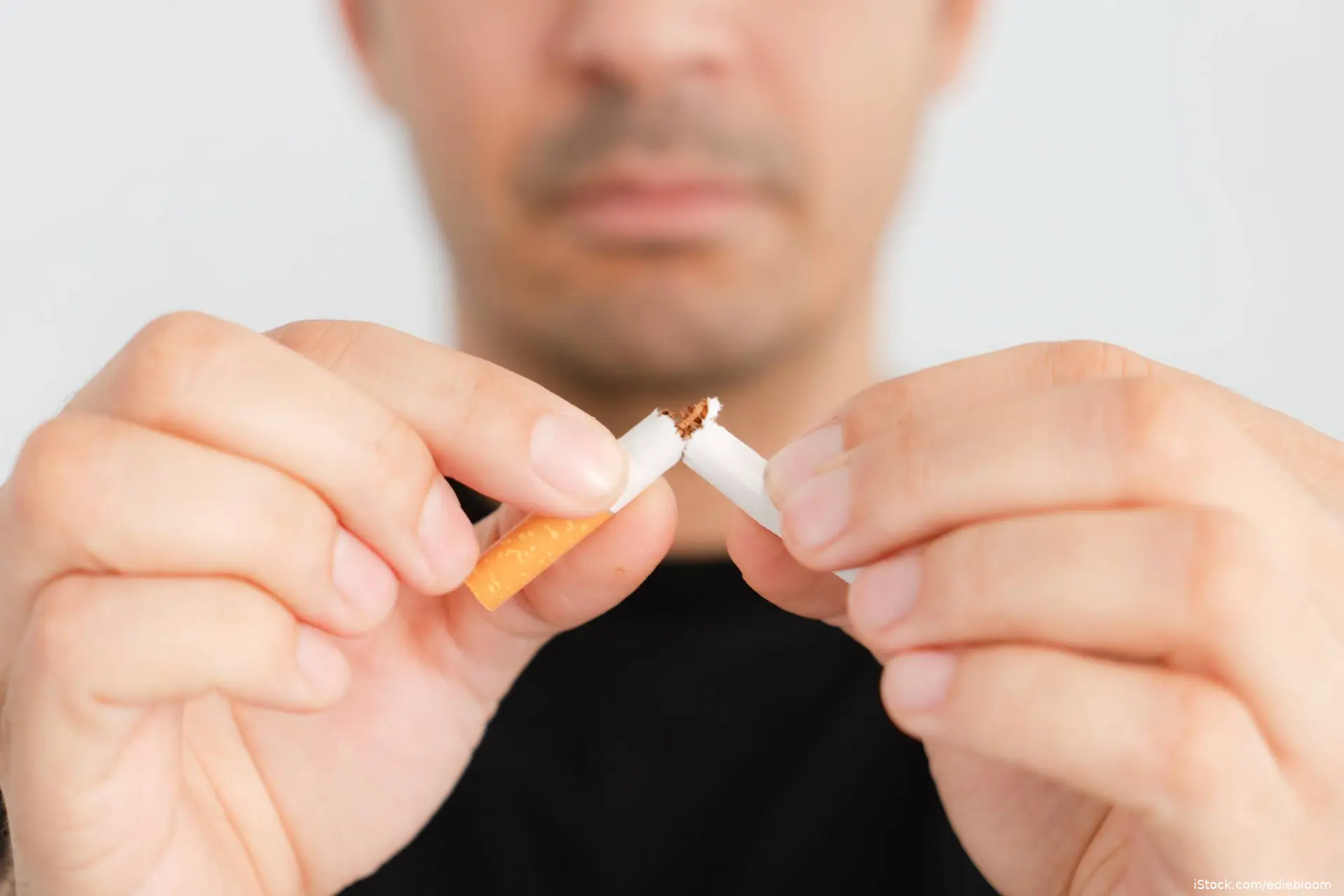 man breaking cigarette in half