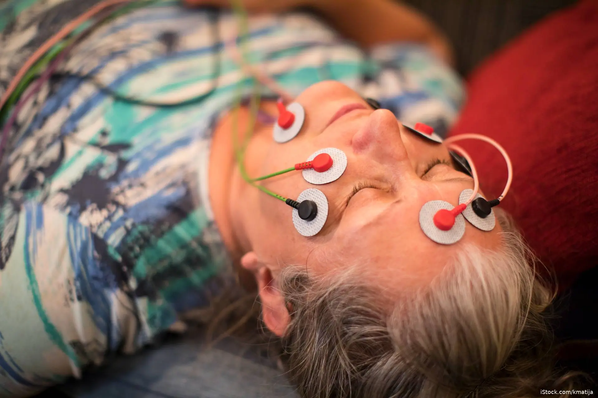 woman lying down with electrical leads attached to her head